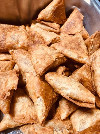 Fried samosas piled on a tray.